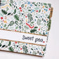 Woodland cottagecore themed pregnancy journal. The cover is multi-colored and has muted tones. Mushrooms, caterpillars, and leaves are on the front cover. There is a personalization strip across the front and the journal is tabbed by trimester.